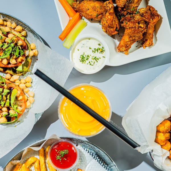 Good Life Clubhaus Juice Bar & Play Café's chicken wings, chickpea avocado toast, fries, and orange juice.