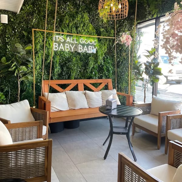 Good Life Clubhaus Juice Bar's seating area with a wooden swing bench, chairs, and a neon sign.