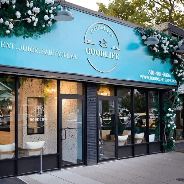 Exterior of Good Life Clubhaus Juice Bar, a modern storefront with a bright blue sign and glass windows.